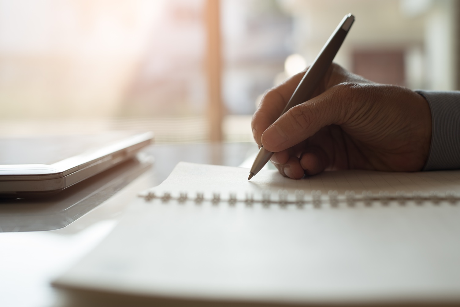 Hand schrijft met een potlood in een kladblok—het creatieve proces van een redacteur in actie